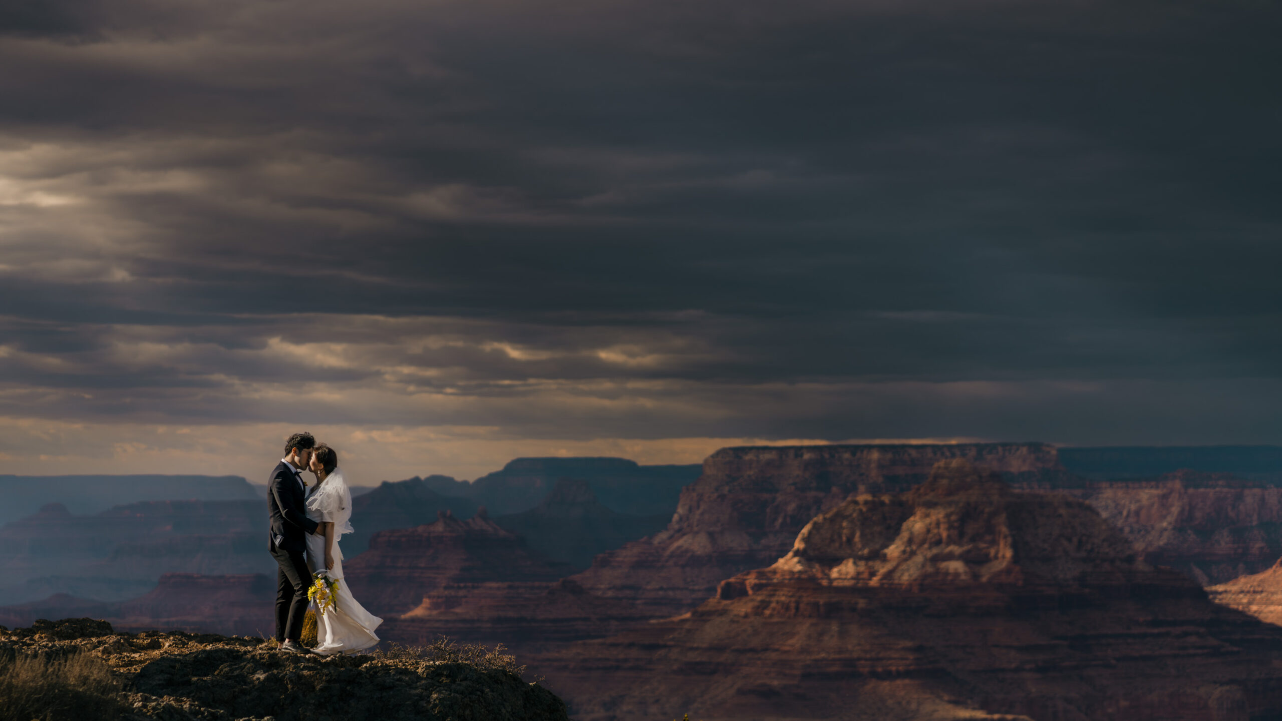 A Wedding Couple kissing in Grand Canyon during their adventure elopement just before the storm rolls in