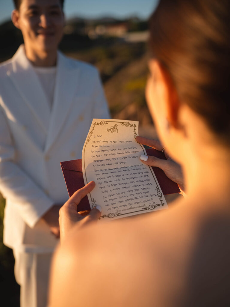 Couple reading vows to each other during their sunset malibu eloepment