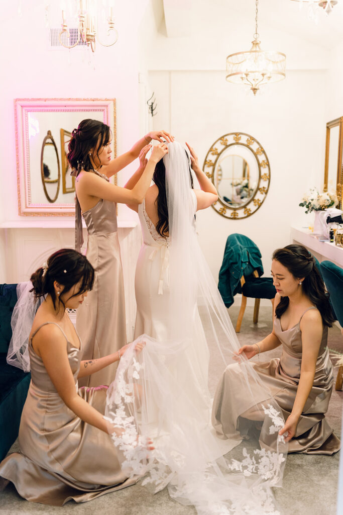 Wedding Timeline Without a Planner: Bridesmaids helping the bride with her wedding dress