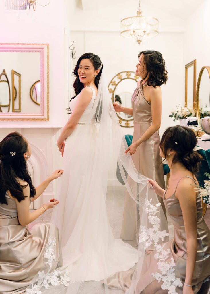 Wedding Timeline Without a Planner: Bridesmaids helping the bride with her wedding dress
