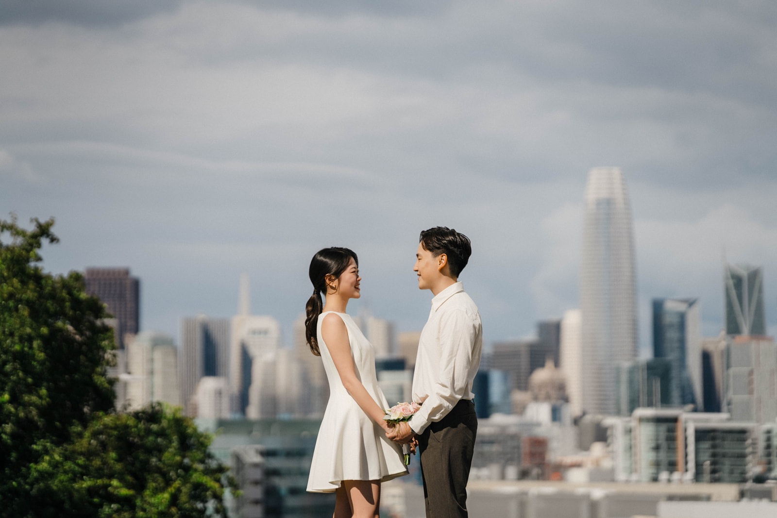 Smiling couple with San Francisco cityscape during engagement session – Eugene Kim Photography