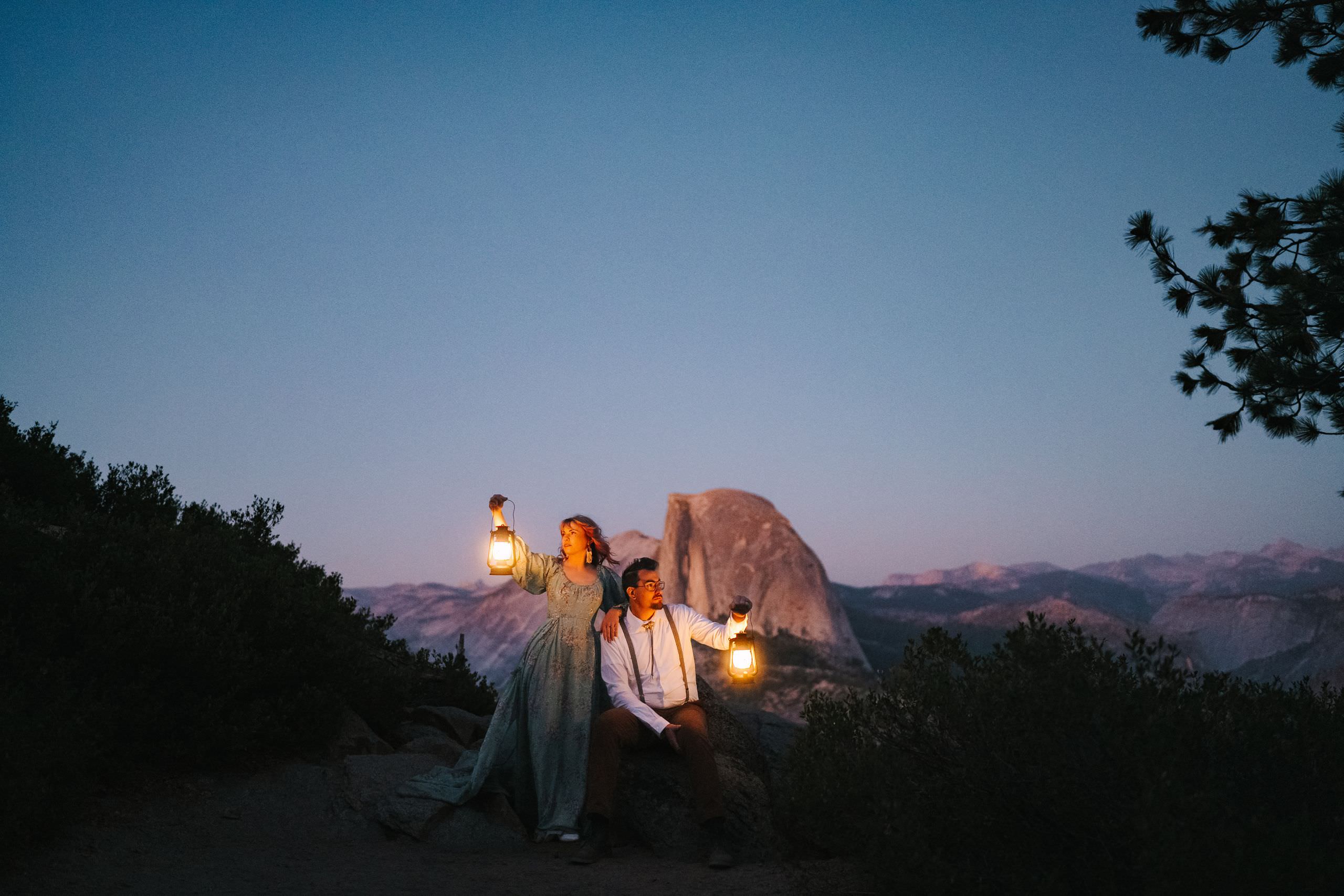 Couple holding lanterns at blue hour in Yosemite with Half Dome in the background