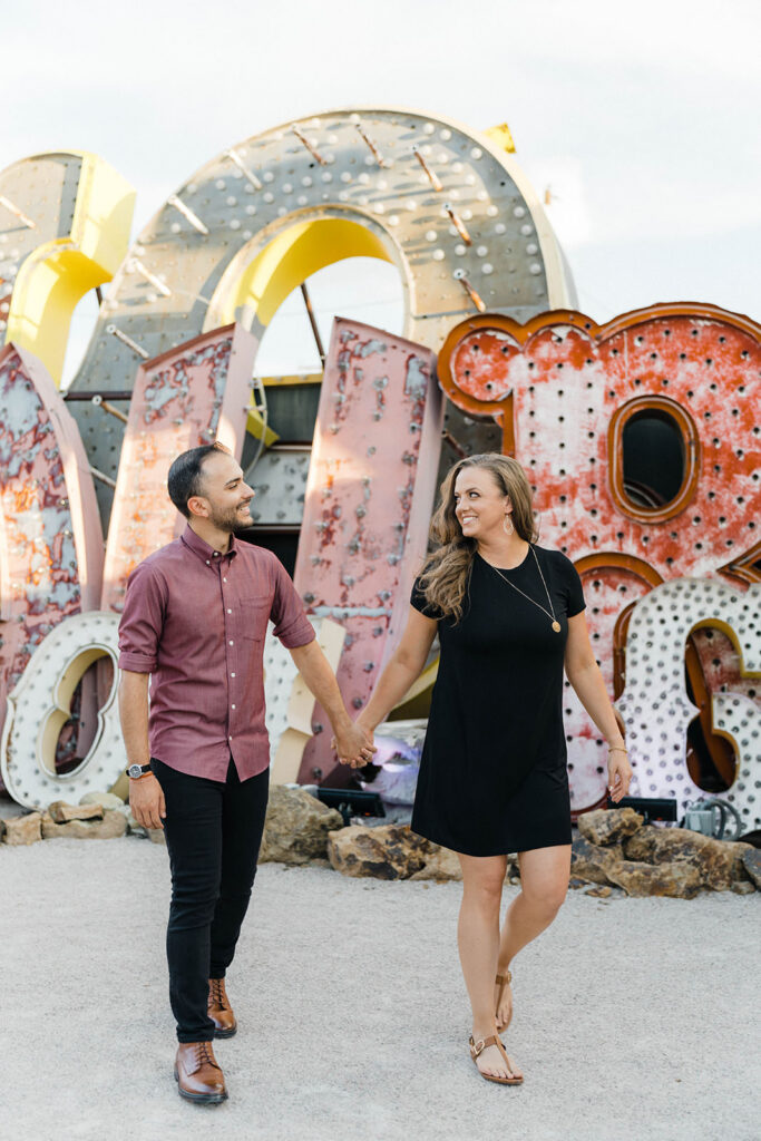 Couple posing among vintage neon signs at the Neon Museum boneyard at dusk