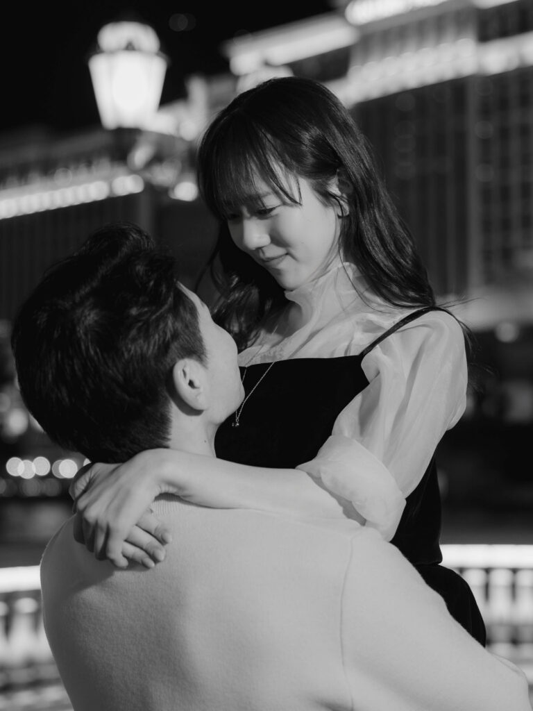 Black and white close-up of a couple forehead to forehead with the Bellagio lit behind them