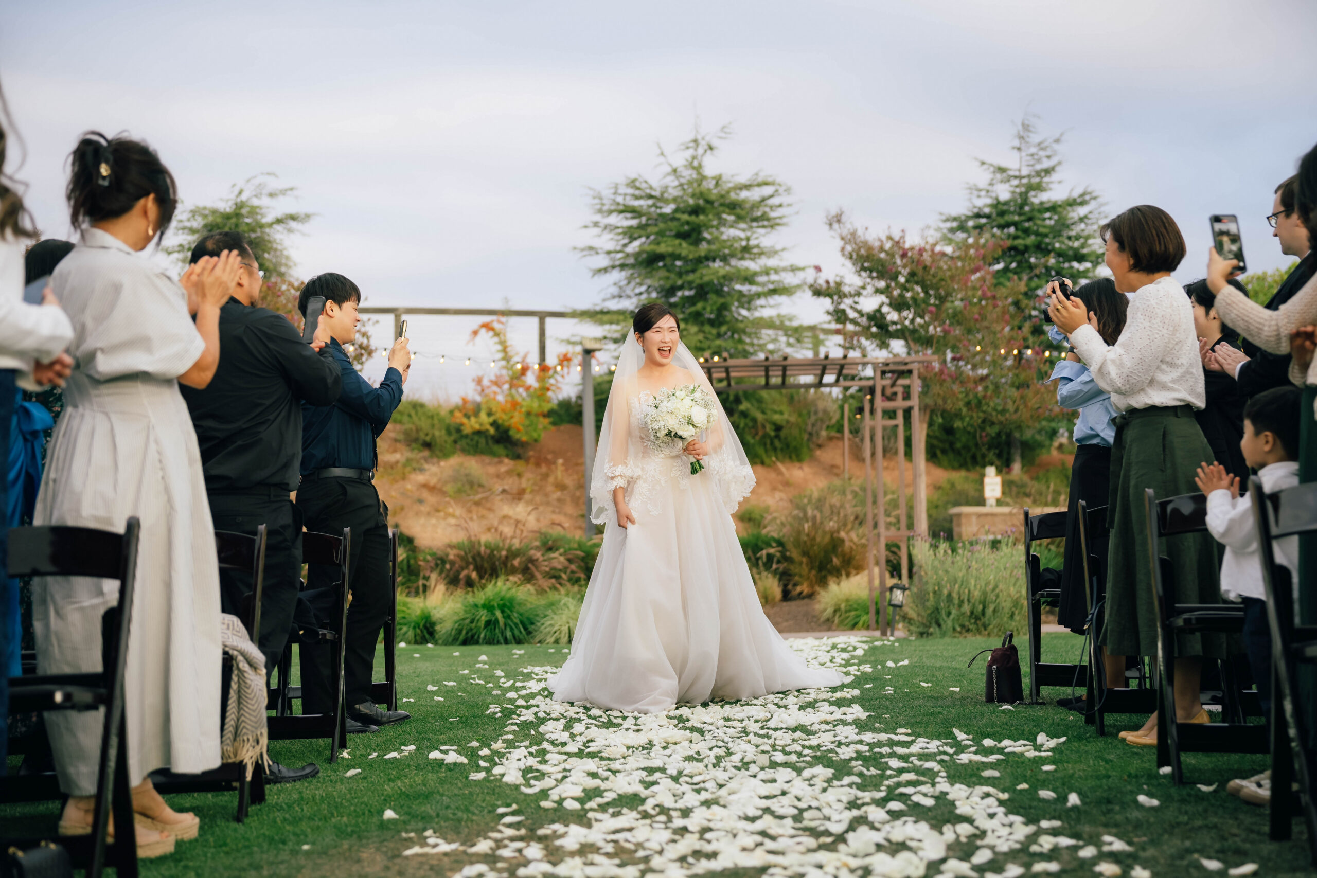 Bride laughing as she walks toward the ceremony with her bouquet.