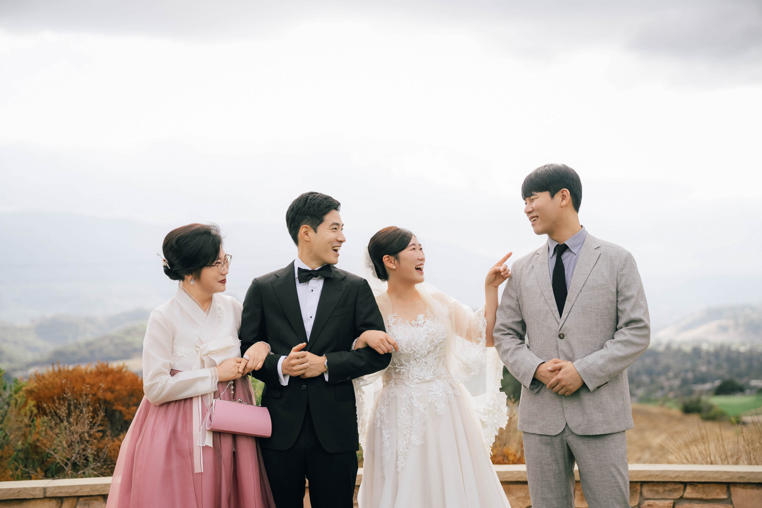 Couple laughing with family, including a woman wearing a pink and white hanbok.