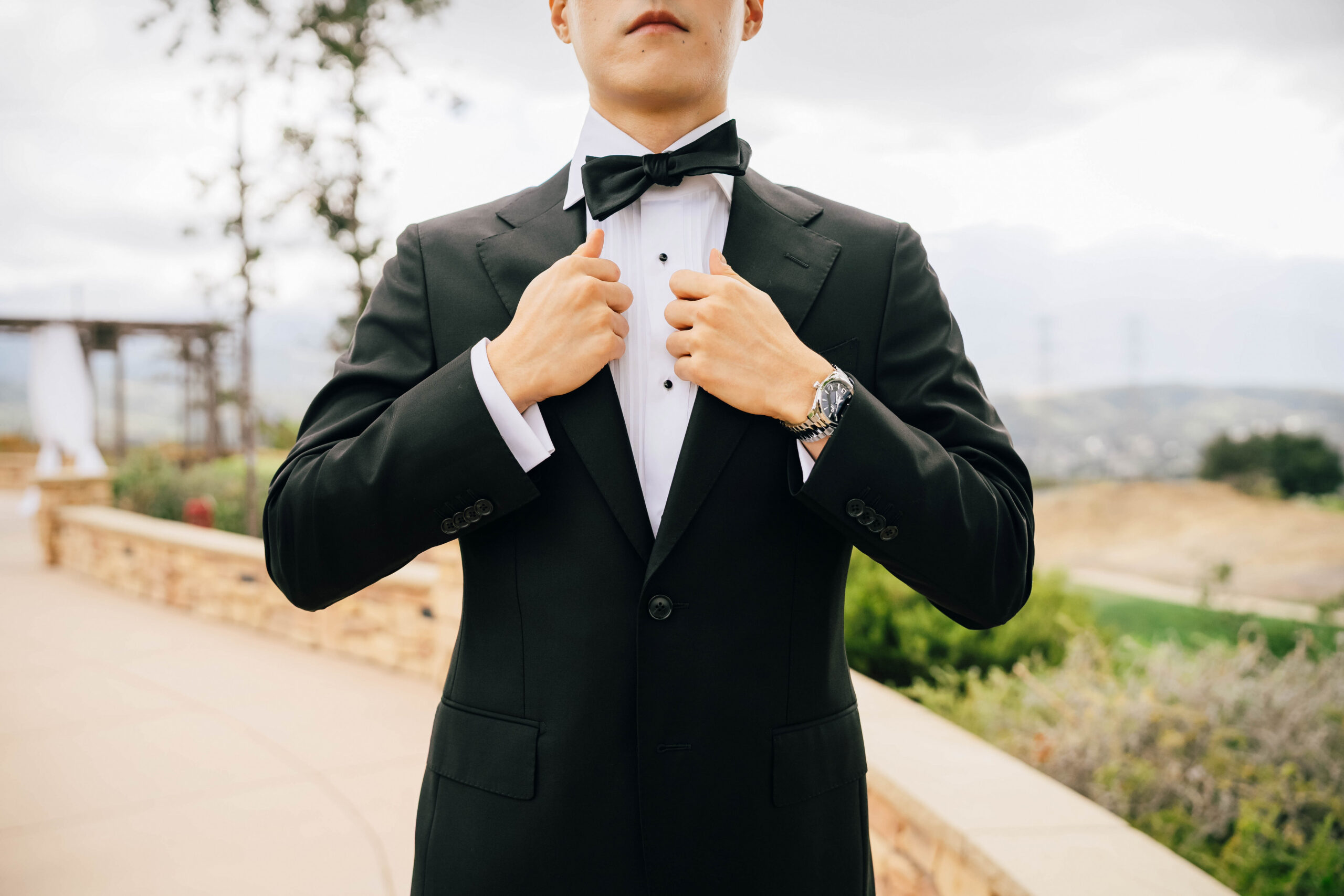 Close view of the groom’s black bow tie and tuxedo lapel.