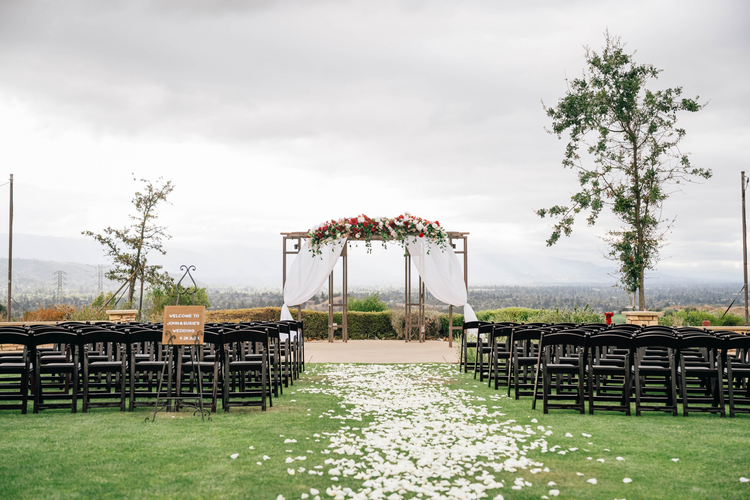 Petal-covered aisle leading to a floral wedding arch at Boulder Ridge Golf Club in San Jose.