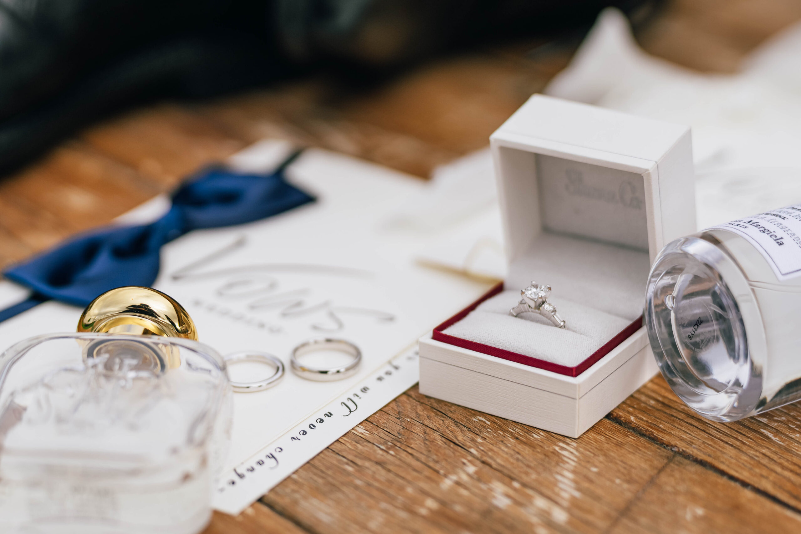 Wedding rings, a ring box, perfume and invitation arranged together.