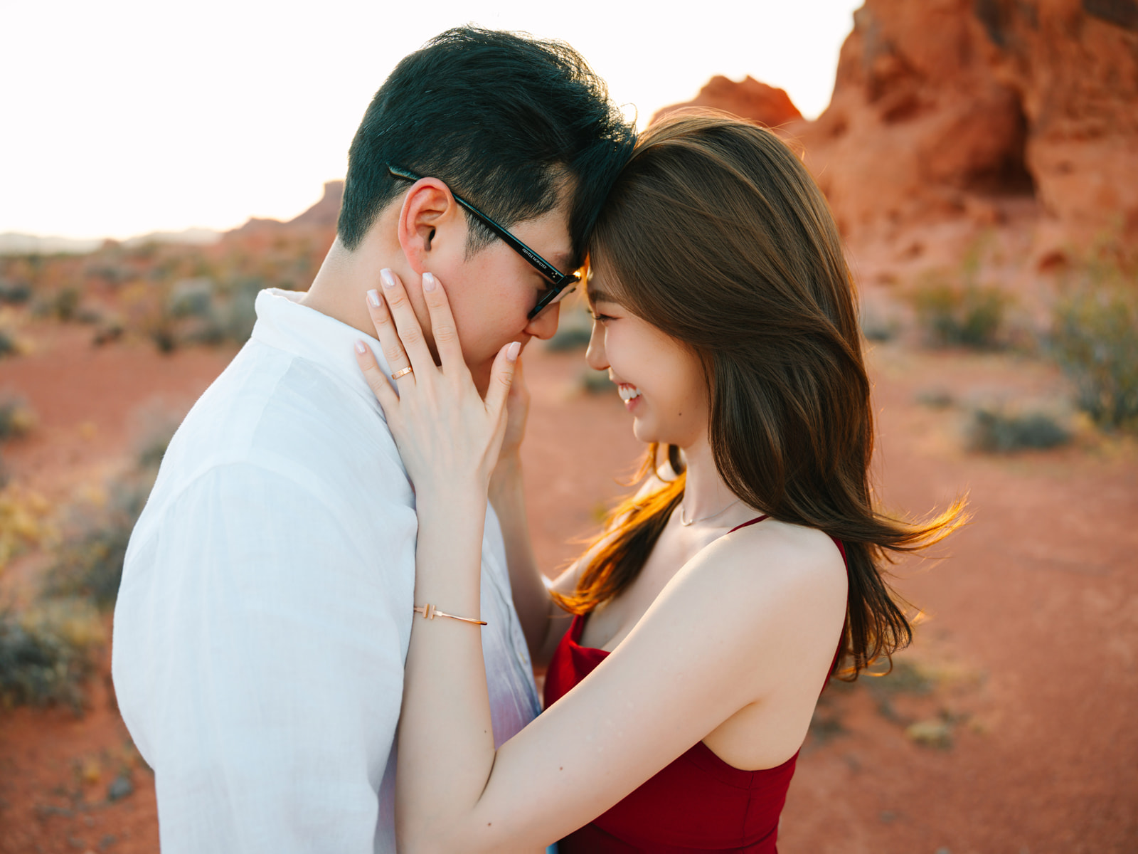 Couple touching foreheads in warm desert light, with a hand resting against a cheek.