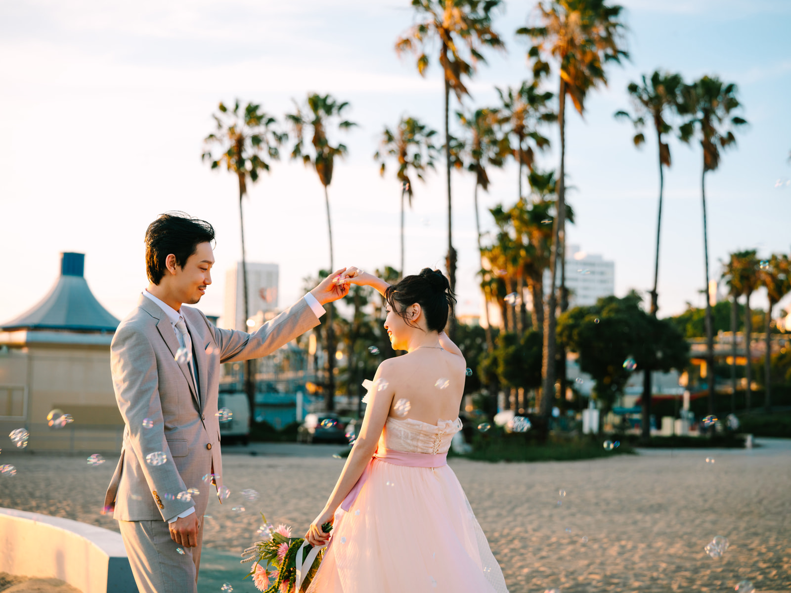 Couple dancing among bubbles with palm trees behind them