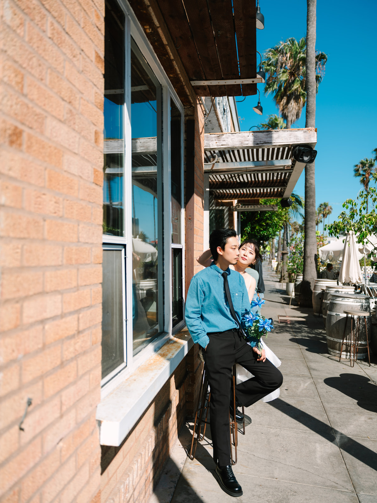 Couple leaning together beside a brick cafe window